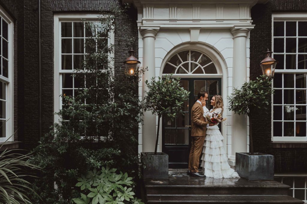 A married couple on the stairs of the secluded garden at luxury boutique hotel The Dylan Amsterdam.