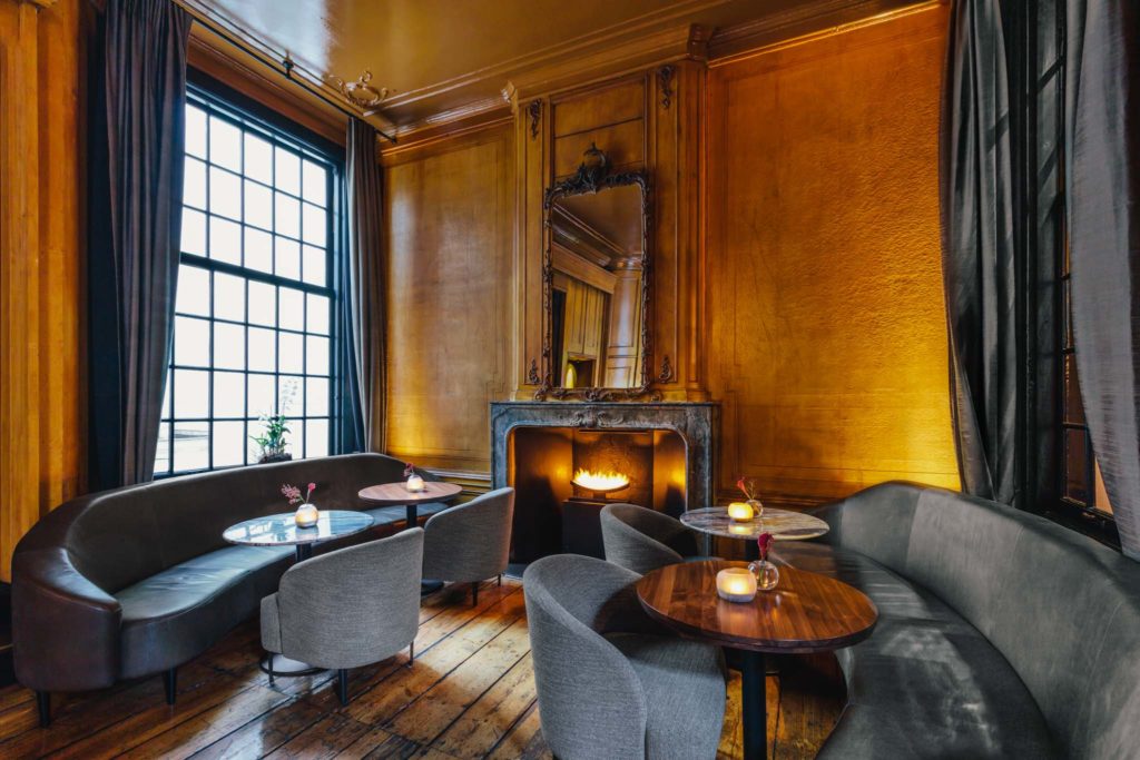 The lounge of Bar Brasserie OCCO, in luxury boutique hotel The Dylan Amsterdam, member of leading hotels of the world. Table next to the fireplace.
