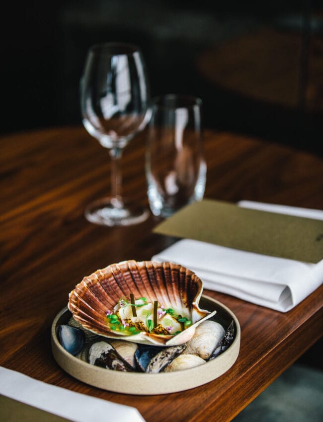 A dish at restaurant até, in luxury boutique hotel The Dylan Amsterdam. This is the scallop, with kombu-scallop dashi, granny smith, preserved Yucatan lime, tear drop pea.