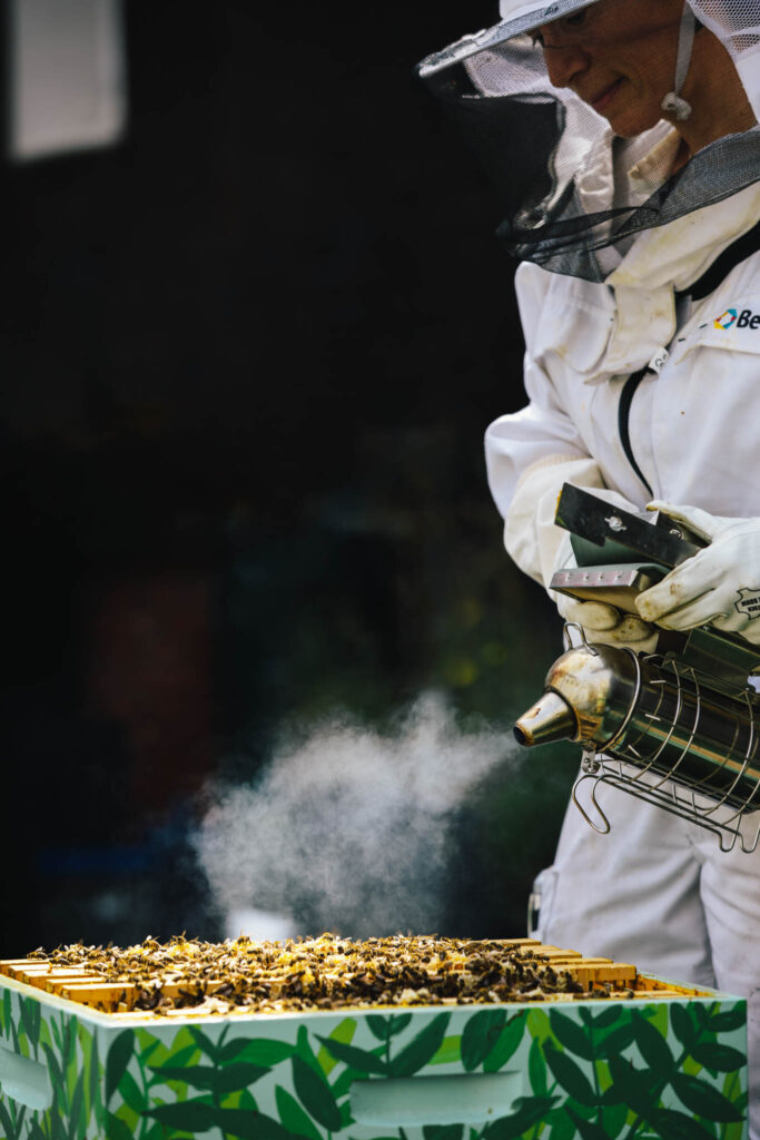 Anoushka de Graaf, beekeeper at The Dylan Amsterdam, working on the beehive with a smoking device.