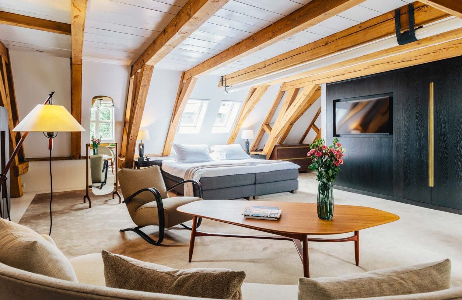 Bedroom in a loft style suite at luxury boutique hotel The Dylan Amsterdam, member of The Leading Hotels of The World. Modern furniture, design elements, historic exposed beams and a flagpole give an authentic décor to this suite.