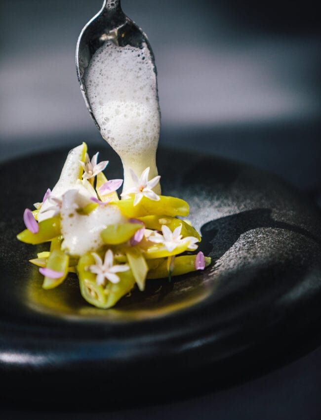 A dish at Michelin starred restaurant Vinkeles in luxury boutique hotel The Dylan Amsterdam leading hotels of the world on a black plate with yellow wax beans.