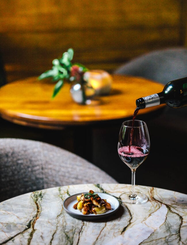 Pouring a glass of wine with a small dish during a High Wine at Bar Brasserie OCCO at The Dylan Amsterdam, part of The Leading Hotels of The World.