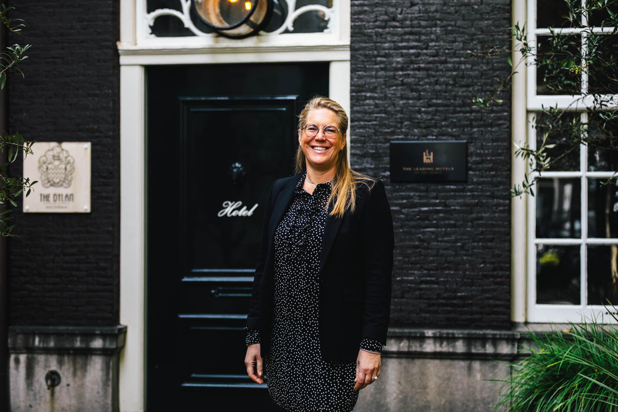 Human resources manager Simone van Hunnik at luxury boutique hotel The Dylan Amsterdam, posing in front of the entrance of the hotel.