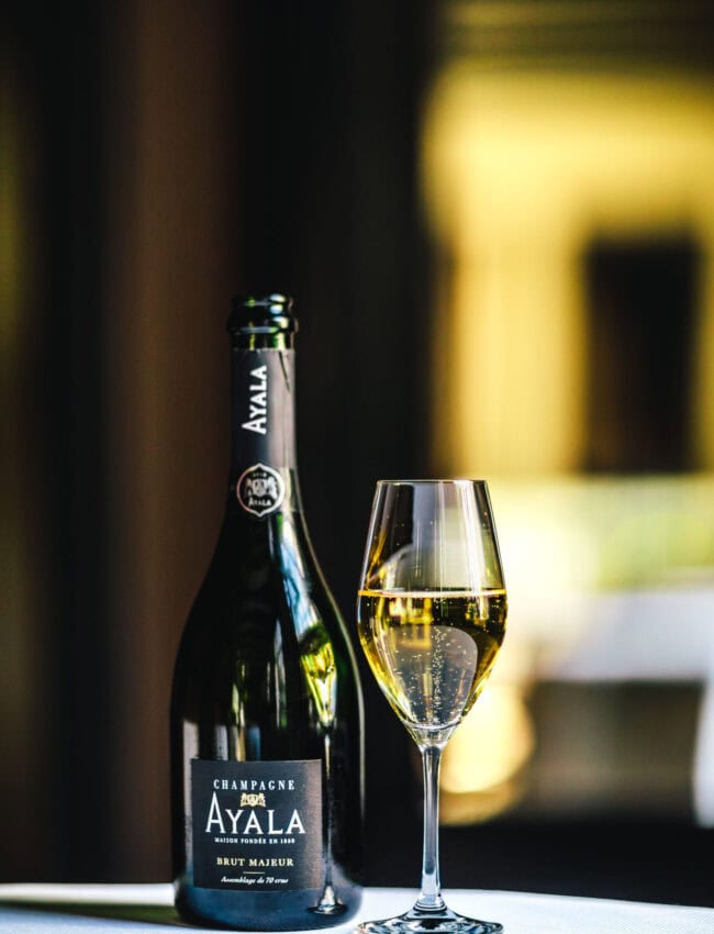 Glass of Ayala Brut Majeur Champagne and a flute glass of bubbly in Vinkeles, a restaurant which gastronomy has been awarded 2 michelin stars at luxury boutique hotel The Dylan Amsterdam, part of the Leading hotels of The World (LHW)